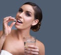Woman, pill and water for healthcare, medication or drugs on a blue studio background. Female person. brunette or model Royalty Free Stock Photo