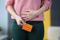 Woman with pills in hands holding lower abdomen at home closeup Royalty Free Stock Photo