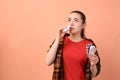 Woman with pills using nasal spray on peach background, space for text