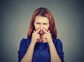 Woman pinches nose looks with disgust something stinks bad smell