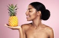 Woman, pineapple and smile for beauty in studio, pink background and healthy vitamin c cosmetics. Happy african model