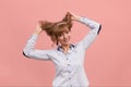 A woman on a pink background pulls her hair, a middle-aged girl in a shirt raises her hair with her hands, problems Royalty Free Stock Photo