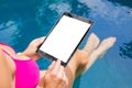 Woman sitting by the pool and using tablet computer. Vertical screen mock up Royalty Free Stock Photo