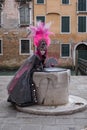 Masked woman in pink and black hand made costume with fan and ornate painted feathered mask at Venice Carnival Royalty Free Stock Photo