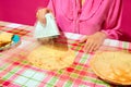 Woman in pink blouse ironing pancake on plaid tablecloth. Meme featuring unexpected ways to prepare food through humor.