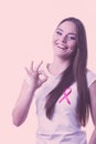 Woman pink cancer ribbon on chest making ok sign