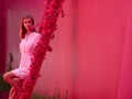 Woman in a pink dress on a bright pink street sits on a staircase decorated with flowers