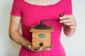 Woman in pink dress holds a manual coffee grinder in her hands Royalty Free Stock Photo