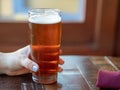 Woman with pink fingernails holding glass of IPA beer on restaurant table Royalty Free Stock Photo