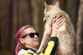 Woman with pink hair hugs beloved Siberian Husky puppy, true love of human and pet