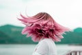 Woman with pink hair standing on the mountain top over blue sea view, photo toned