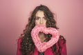 Woman with pink heart in mouth. valentines day and love concept. pretty girl with long curly hair on pink background