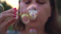 Woman with pink nails blowing soap bubbles Face close up Slow motion