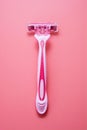 Woman pink plastic razor isolated on pink background. Disposable female shavers. Skin care