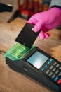 Woman in pink protective glove paying with contactless card at food store during quarantine. Closeup view of terminal Royalty Free Stock Photo