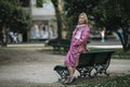 A woman in a pink raincoat stands near a park bench. Royalty Free Stock Photo