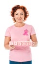 woman with pink ribbon holding blocks with word cancer and smiling at camera