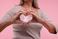 Woman with pink ribbon showing heart gesture on color background, closeup. Breast cancer awareness Royalty Free Stock Photo