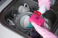 A woman in pink rubber gloves pouring detergent on a kitchen sponge against the backdrop of dirty dishes in the sink. Close-up. Royalty Free Stock Photo