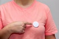 Woman in pink shirt pointing at a shiny round button. Isolated pin badge mockup