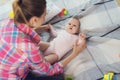 A woman in a pink shirt sits on the floor in living room and plays with her little child. Child really likes to play. Royalty Free Stock Photo