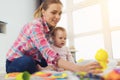 A woman in a pink shirt sits on the floor in living room and plays with her little child. Child really likes to play. Royalty Free Stock Photo