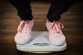 Woman with pink sneakers on bathroom weight scale Royalty Free Stock Photo