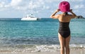 Woman with Pink Straw Hat Looking at a Catamaran