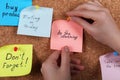 Woman pinning paper note with phrase Do The Cleaning to cork board, closeup