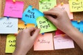 Woman pinning paper note with phrase Don`t Forget to cork board, closeup