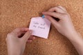 Woman pinning paper note with phrase Take Out The Trash to cork board, closeup