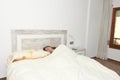 Woman placidly sleeping in bed in her large bedroom. Royalty Free Stock Photo