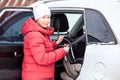 Woman placing baby safety seat in the car, fastening with belt. Rear seat of suv