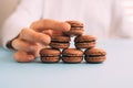 Woman placing macarons on heap on blue table