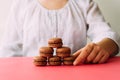 Woman placing macarons on heap on pink table