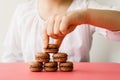 Woman placing macaroons on heap on pink table