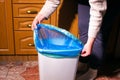 Woman placing new blue garbage bag into empty trash bin in home kitchen Royalty Free Stock Photo