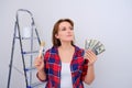 A woman in a plaid shirt and money to renovate a new home. Dollars for the decoration of the built apartment Royalty Free Stock Photo