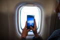 Woman in plane taking photo of clouds and sky on her smartphone.