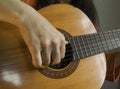 Woman playing an acoustic guitar, hand is visible close-up