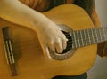 Woman playing an acoustic guitar, hand is visible close-up