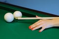 Woman hand holds a cue for striking the white billiard ball Royalty Free Stock Photo