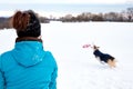 Woman is playing frisbee or flying disc with her dog in the snow Royalty Free Stock Photo