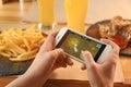 Woman playing game using smartphone at table with snacks
