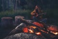 A woman playing guitar at a campfire in the forest, creating a cozy and magical atmosphere. Royalty Free Stock Photo
