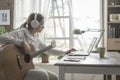 Woman playing guitar and connecting with her laptop Royalty Free Stock Photo