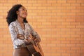 Woman playing guitar outside looking up on a brick wall background Royalty Free Stock Photo