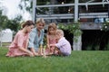 Woman playing with kids in the garden, outdoor garden games, sitting on grass.