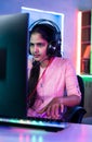 Woman playing live video game on computer by talking to players on headphones at home - concept of live streamer Royalty Free Stock Photo