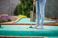 Woman playing mini golf and trying putting ball into hole Royalty Free Stock Photo